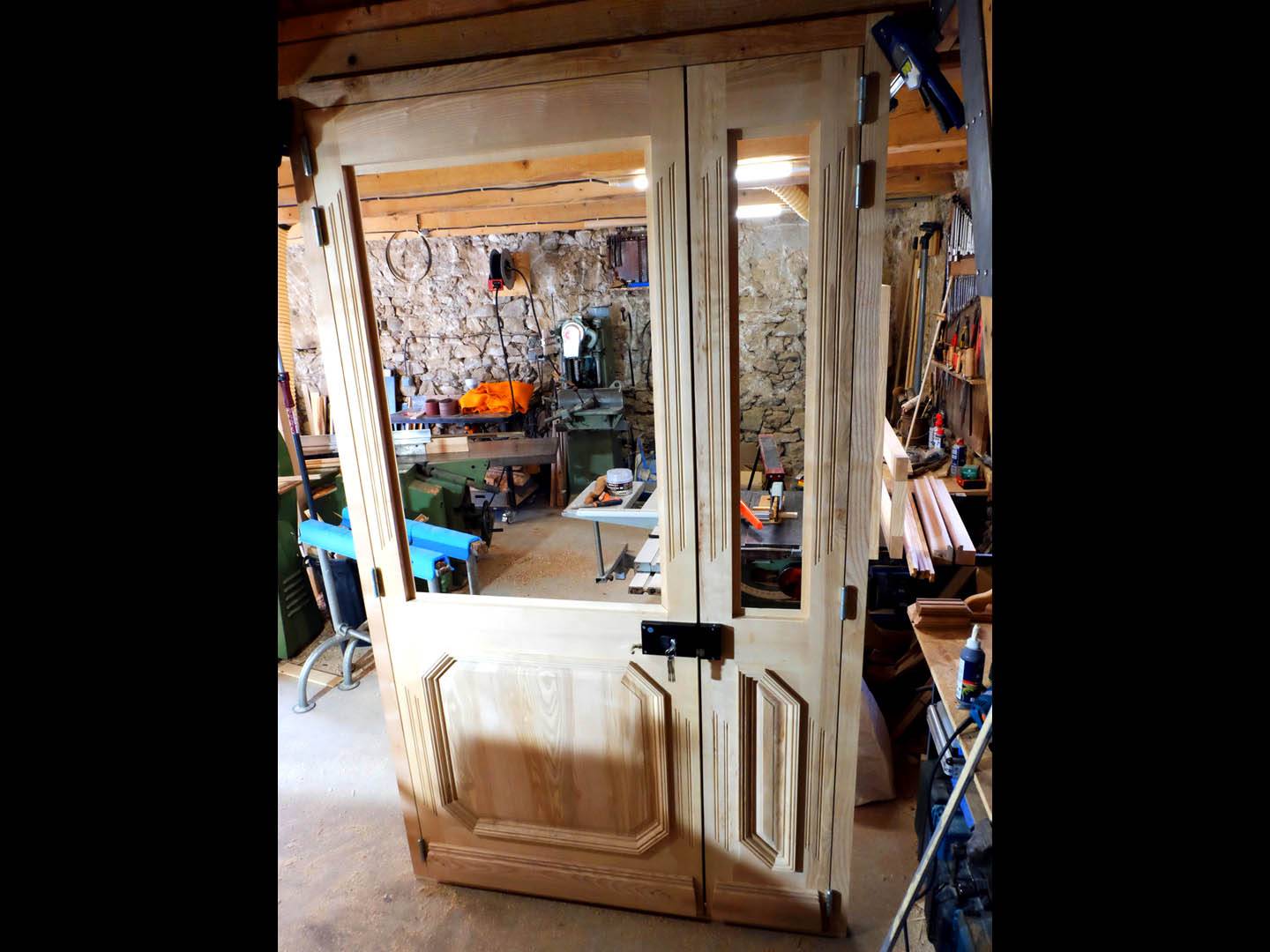 Porte d'entrée pour un sas d'immeuble. Fabriquée entièrement en frêne, moulure à grand cadre, imposte et ornementation. Atelier de la baleine. 2025