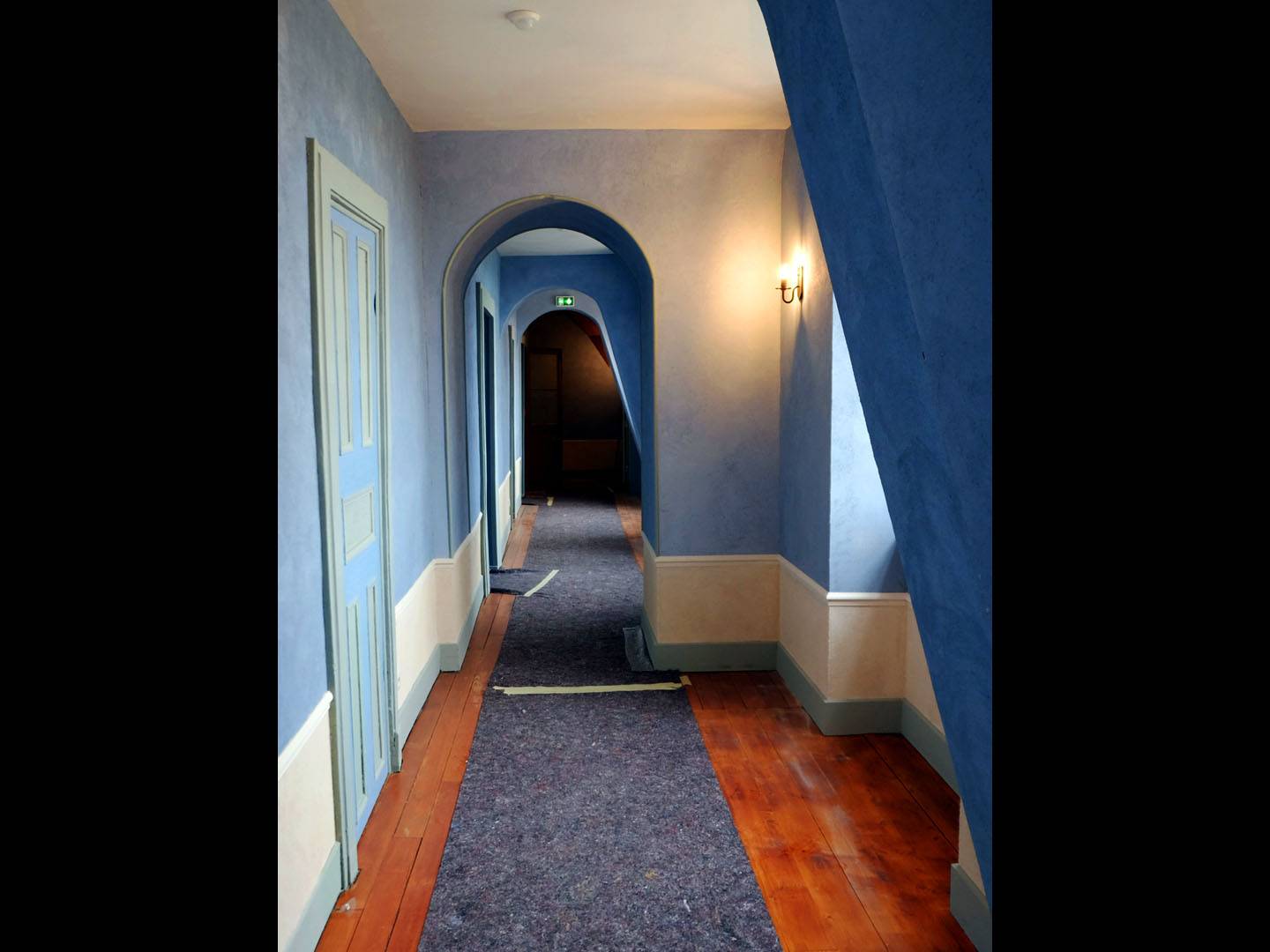 Restauration intérieure d'un château. Pose des plinthes, cimaises et baguette d'angle. Vue du couloir après les finitions des peintres. Atelier de la baleine. 2022
