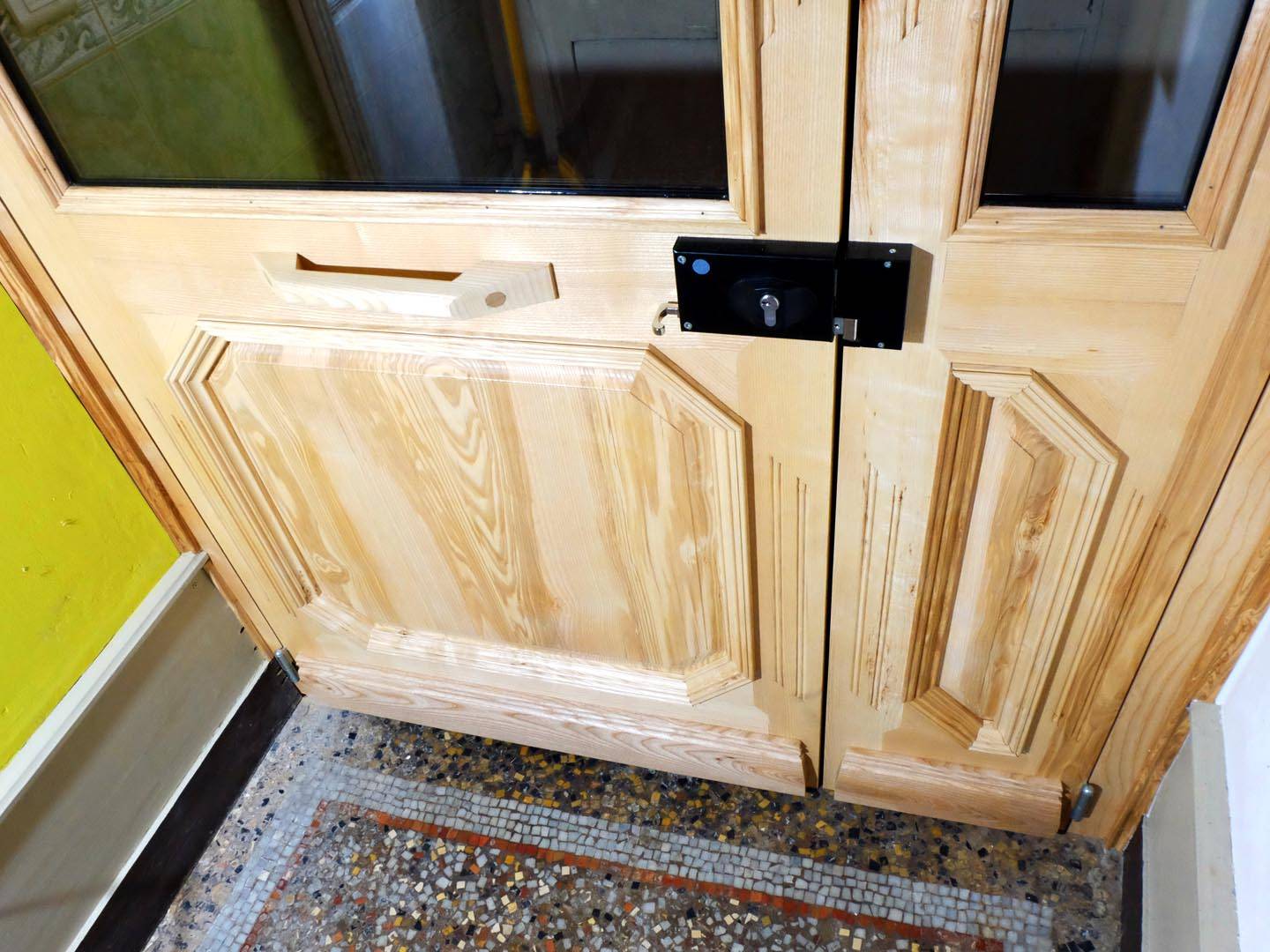 Porte d'entrée pour un sas d'immeuble. Fabriquée entièrement en frêne, moulure à grand cadre, imposte et ornementation. Atelier de la baleine. 2025