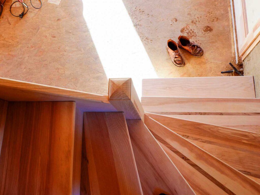Escalier quart tournant à marches balancées, avec contre marche. L'escalier est entièrement en bois massif, en frêne avec des incrustations de latte de noyer. Atelier de la baleine. 2021