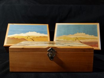 Boites à secret ornées d'une marqueterie de paysage imaginaire. La structure apparente est en merisier et les placages intérieurs sont en loupe d'amboine et ronce de noyer. Atelier de la baleine. 2026.