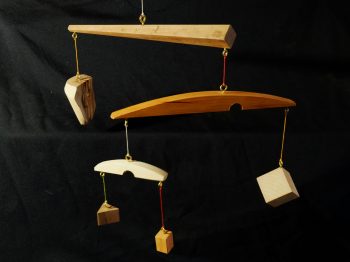 Série des "mobiles ésotériques". Mobiles de décoration dont le vent fait se mouvoir des éléments géométriques et abstraits, et révèle les tensions physiques entre eux. Différentes essences utilisées: olivier, if, cyprès, noyer, châtaignier, chêne... Atelier de la baleine. 2026