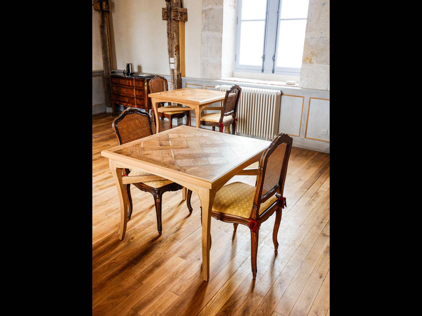 Tables de salle à manger. Ces tables ont été fabriquées en chêne, avec des pieds galbés traditionnels et deux traverses croisées. Les plateaux des tables sont faits d'un parquet Versailles restauré. Atelier de la baleine. 2023