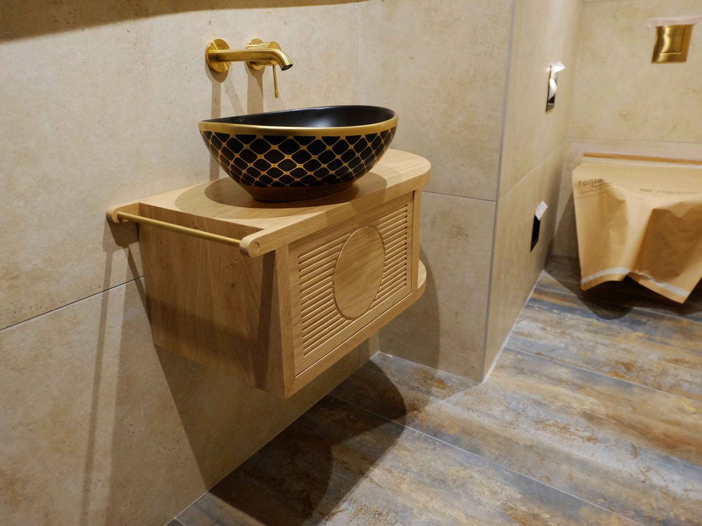 Petite console suspendue au mur accueillant une vasque. La façade du tiroir est ornée d'un dessin géométrique fait par un défonçage de petites gorges. Essence de bois en chêne et finition vernie. Atelier de la baleine. 2025.