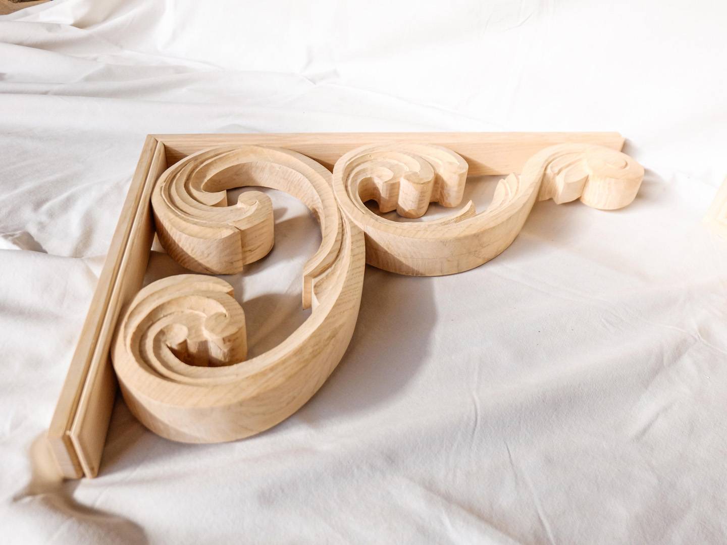 Corniches sculptées dans du frêne massif. Elles sont installées dans le prolongement de la structure d'un auvent. Atelier de la baleine. 2023