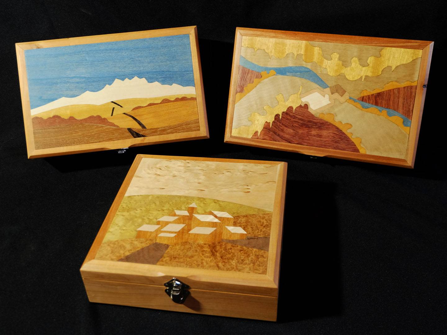 Boites à secret ornées d'une marqueterie de paysage imaginaire. La structure apparente est en merisier et les placages intérieurs sont en loupe d'amboine et ronce de noyer. Atelier de la baleine. 2026.