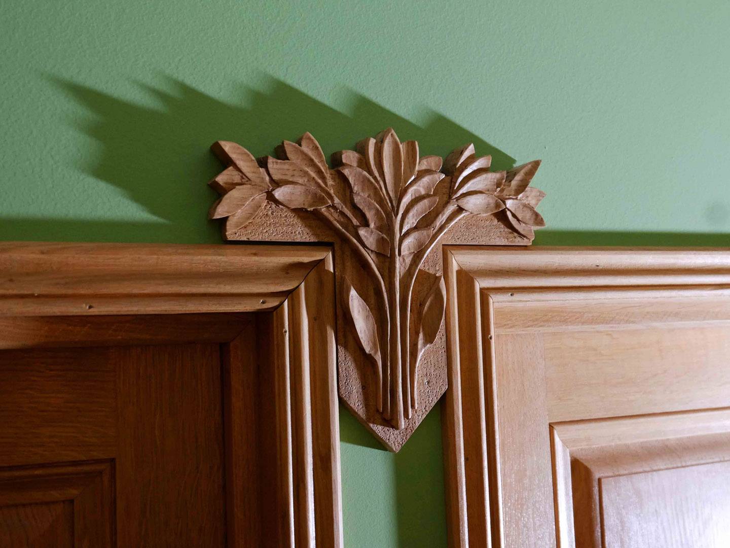 Petit bas-relief sculpté d'une ornementation florale, cachant un joint de construction entre deux cadre de porte. Essence : chêne. Atelier de la baleine. 2025.
